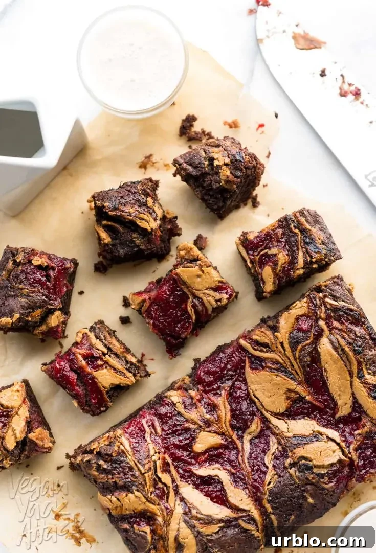 Image of brownies on parchment paper, with peanut butter and jelly swirled into the tops