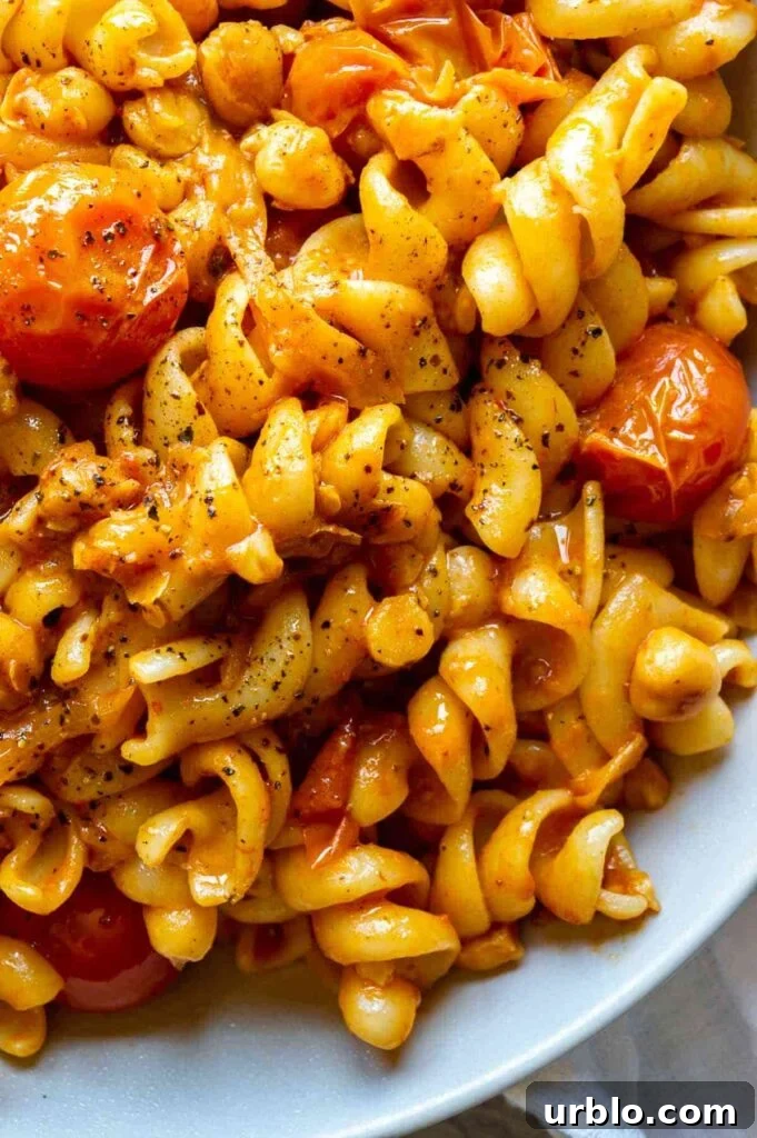 A close up of pasta with orange sauce and cherry tomatoes