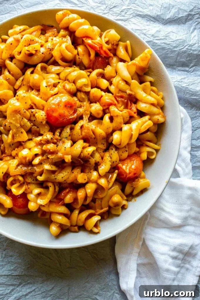 Top down view of a bowl of fusilli pasta with harissa sauce and cherry tomatoes