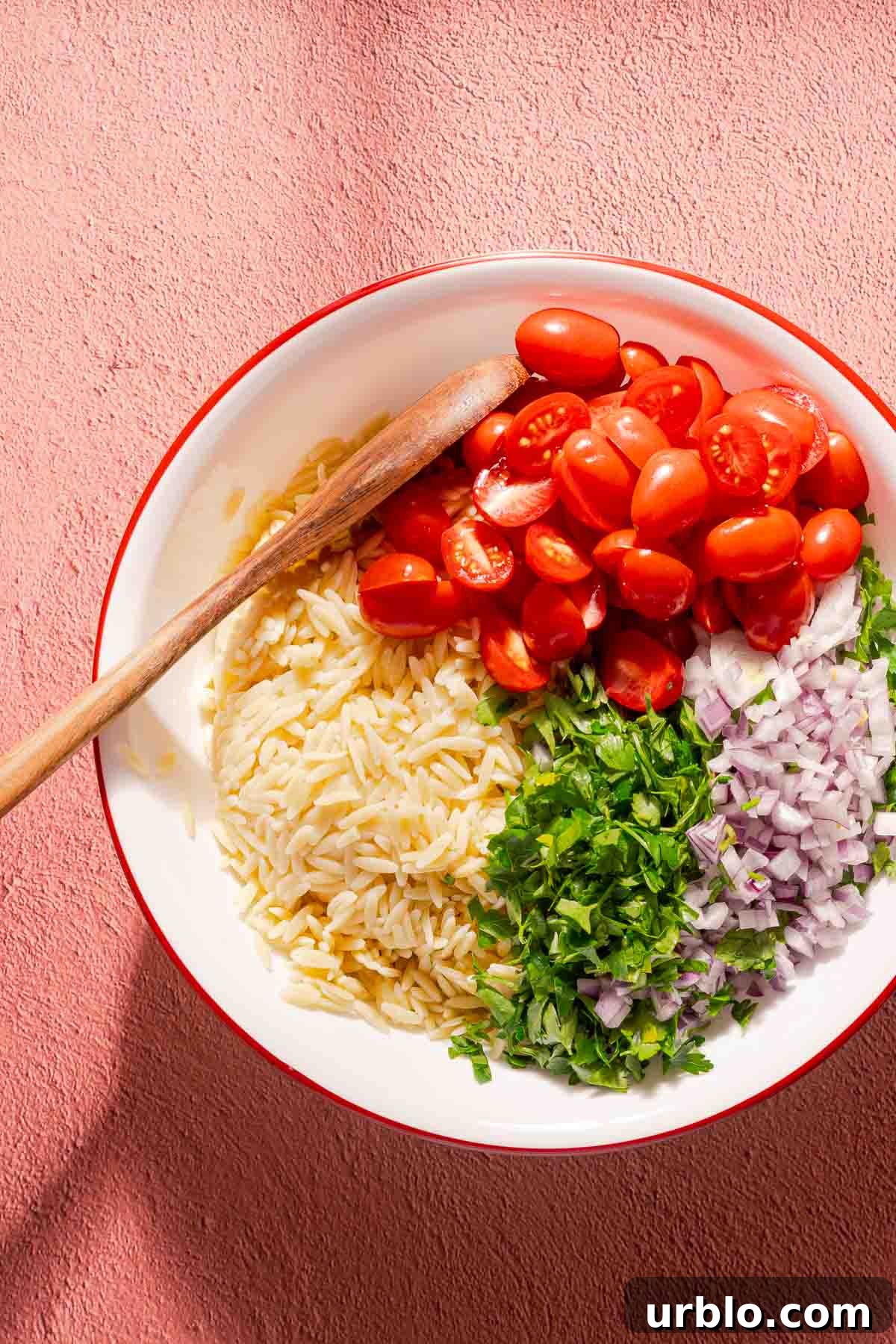 orzo tomatoes parsley and red onion in a bowl.