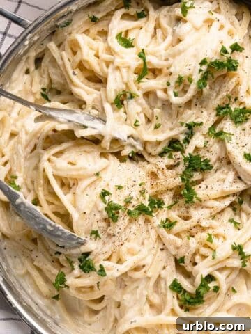 pan of cream cheese pasta garnished with parsley and black pepper