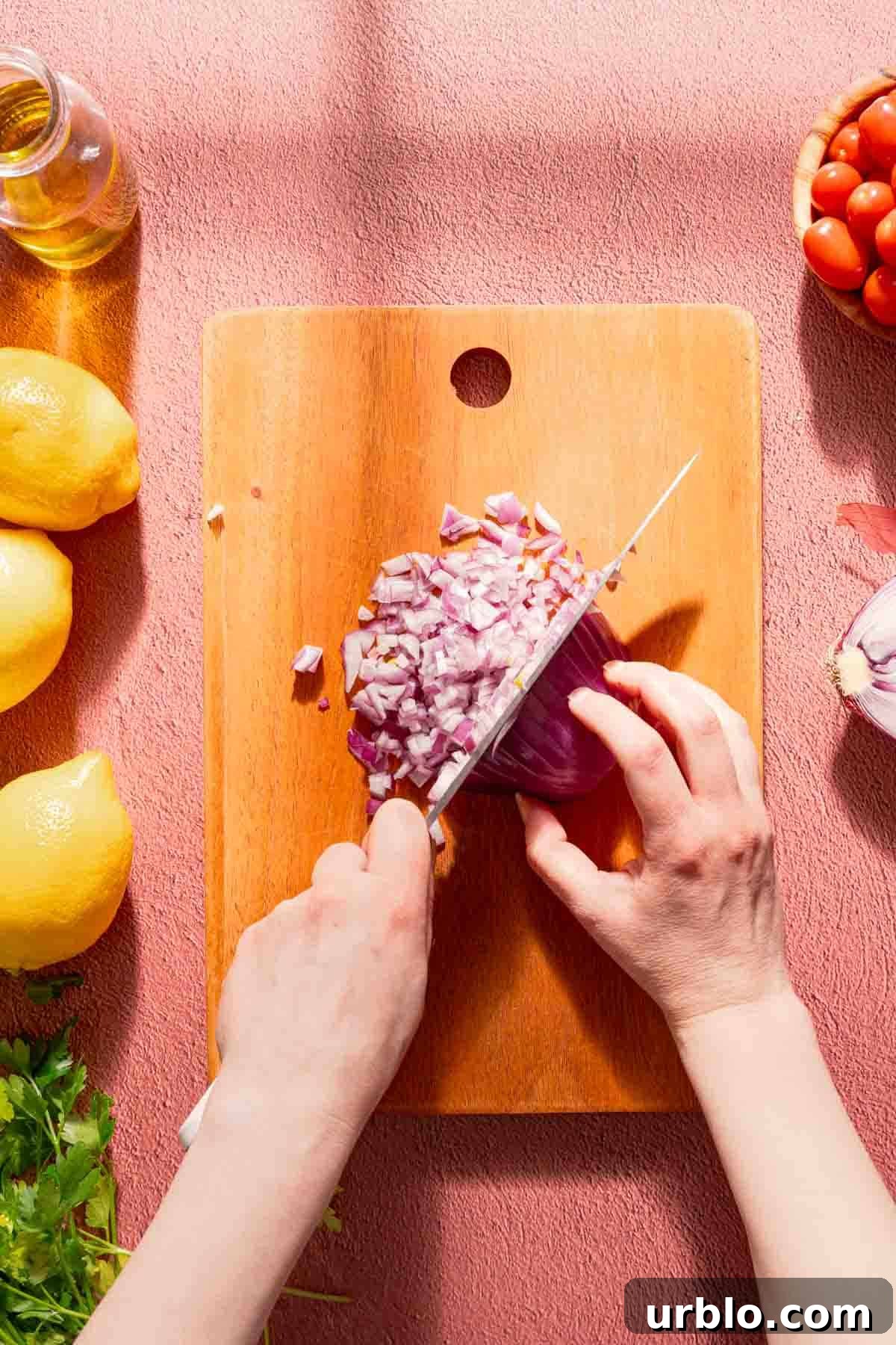 red onion being chopped on wooden cutting board.