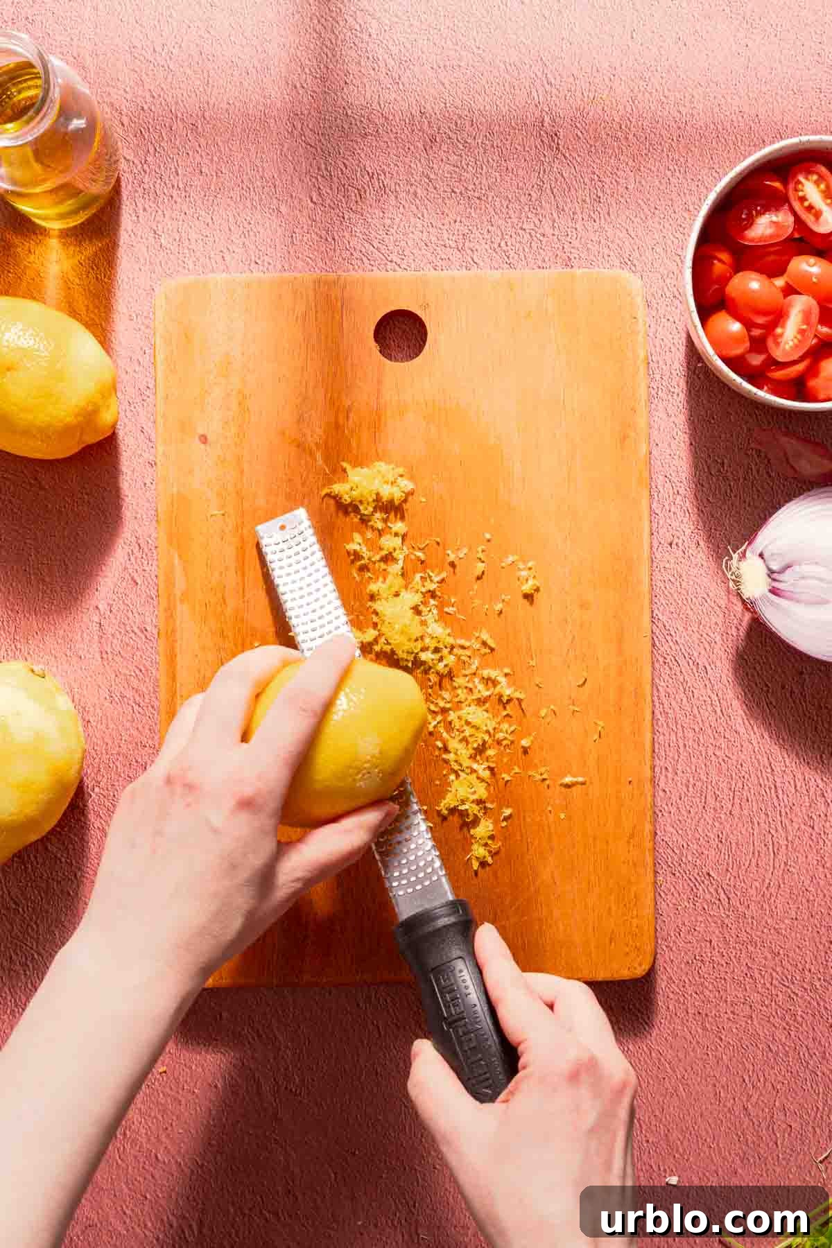 lemon being zested with microplane over wooden cutting board.