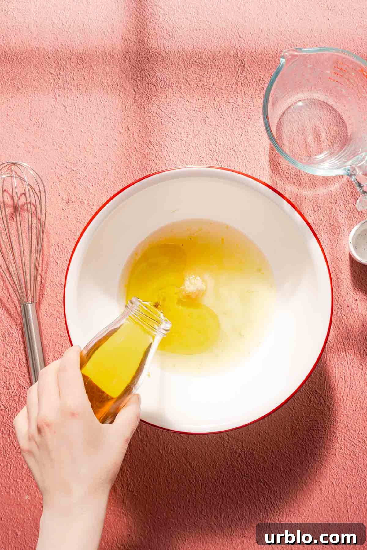 olive oil being poured into a bowl with lemon juice and zest inside.