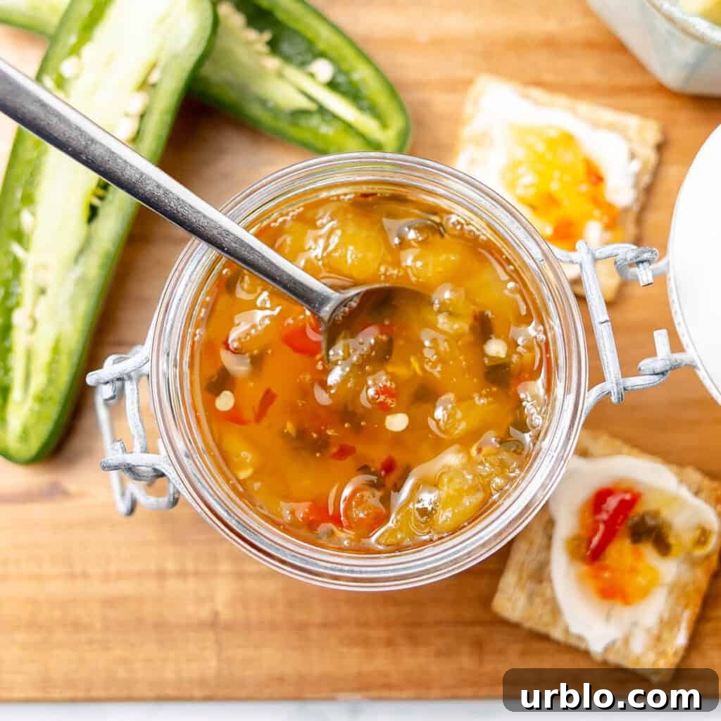 An open jar of pepper jelly with a spoon inside