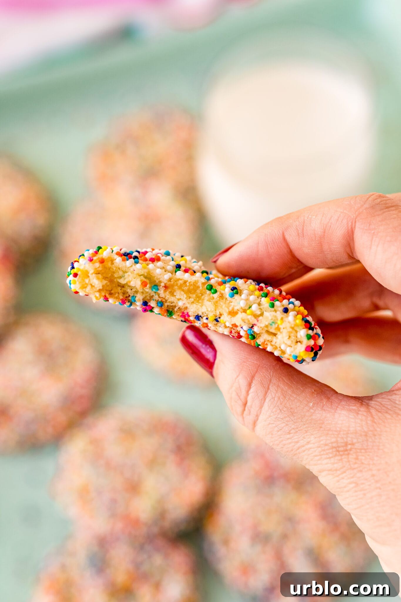 woman's hand holding funfetti cake mix cookie with bite taken out of it