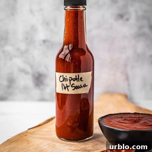 Bottle of hot sauce on a board next to a small bowl with the same hot sauce.