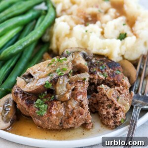 Salisbury steak with mashed potatoes and green beans on a white plate
