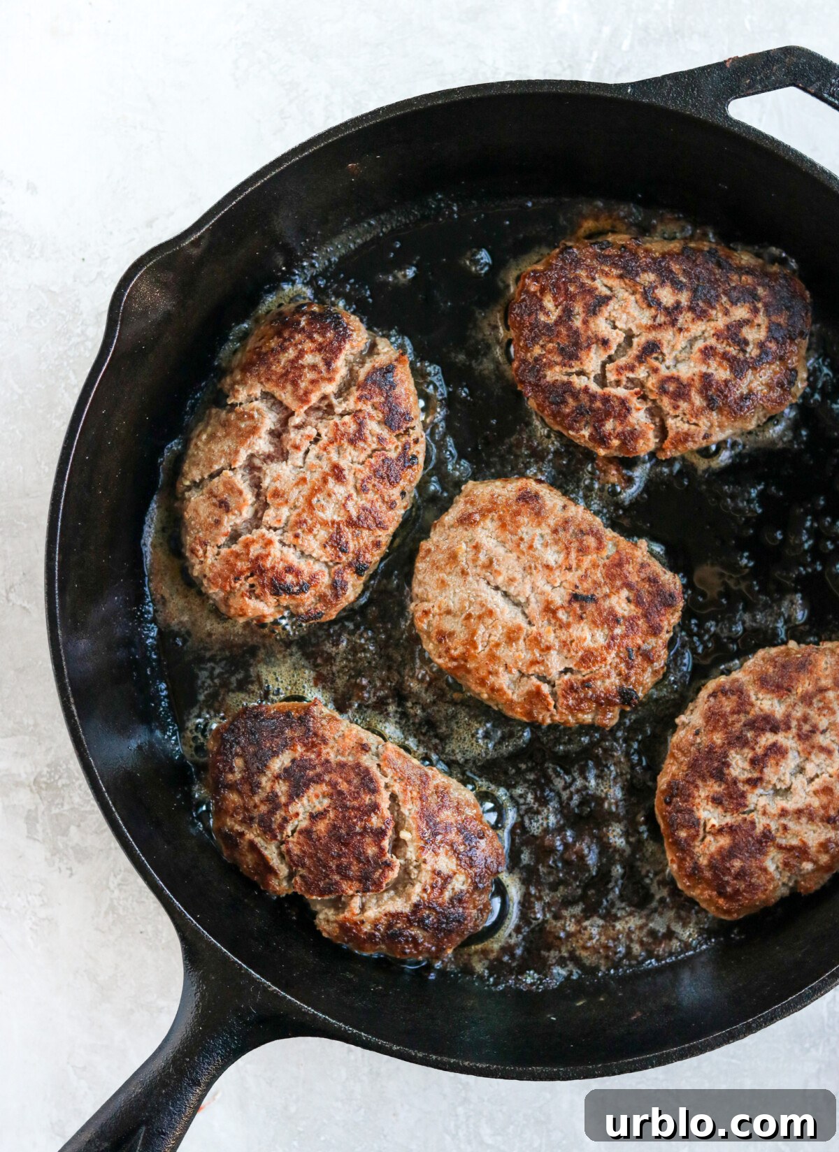 hamburger steaks frying in a cast iron skillet