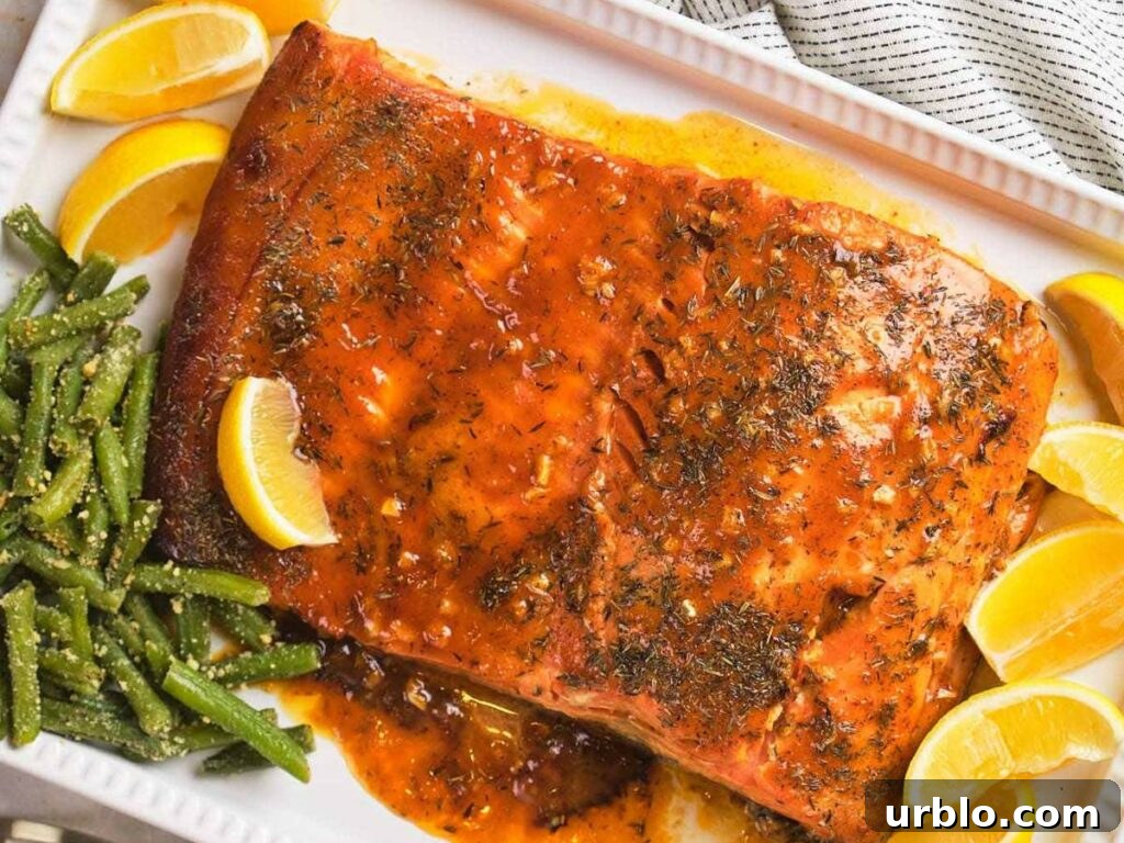 Honey mustard glazed salmon with herbs and lemon wedges on a white platter, served with seasoned green beans.