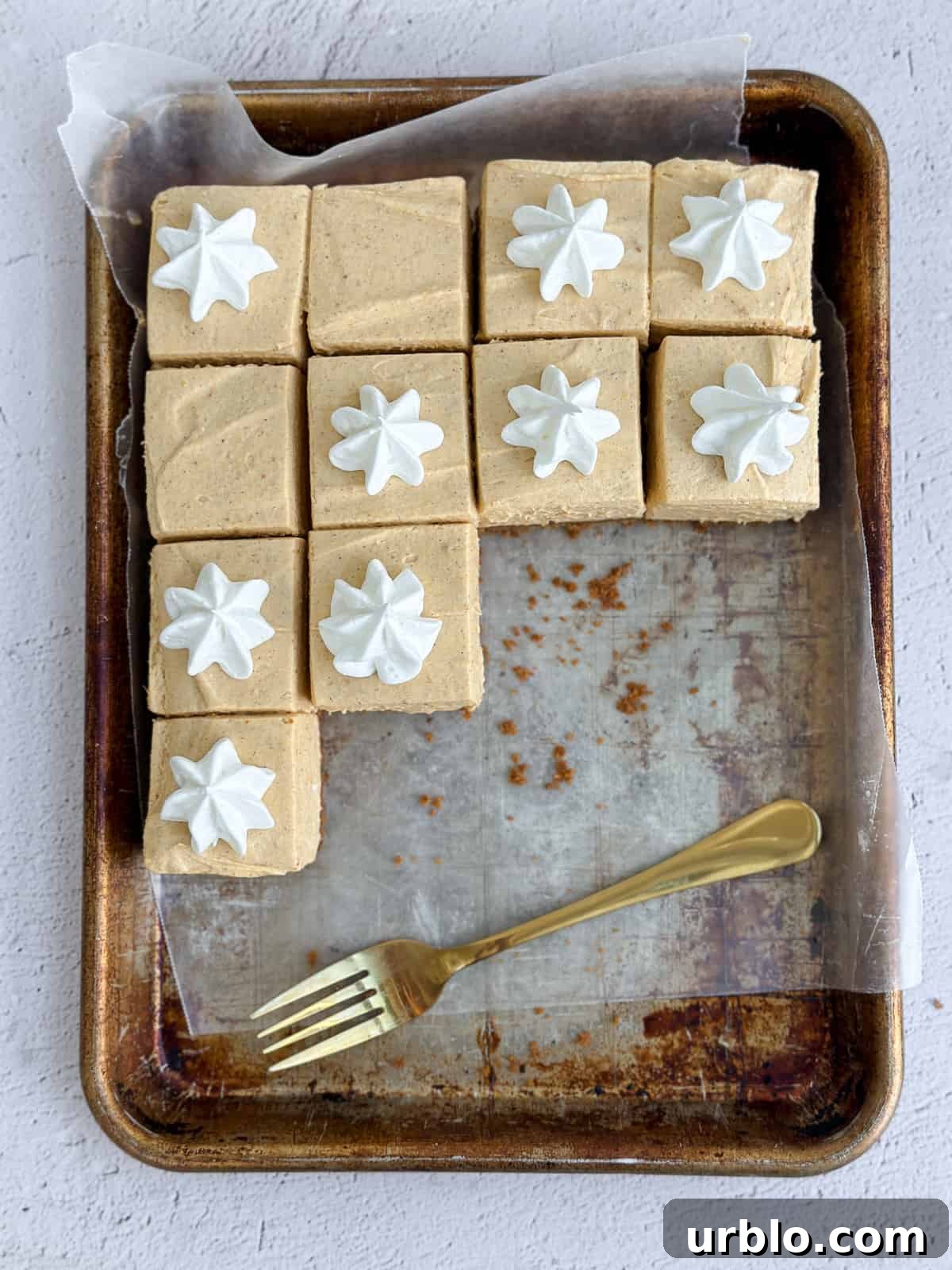 a bunch of the no bake pumpkin cheesecake bars on a baking sheet with a fork.