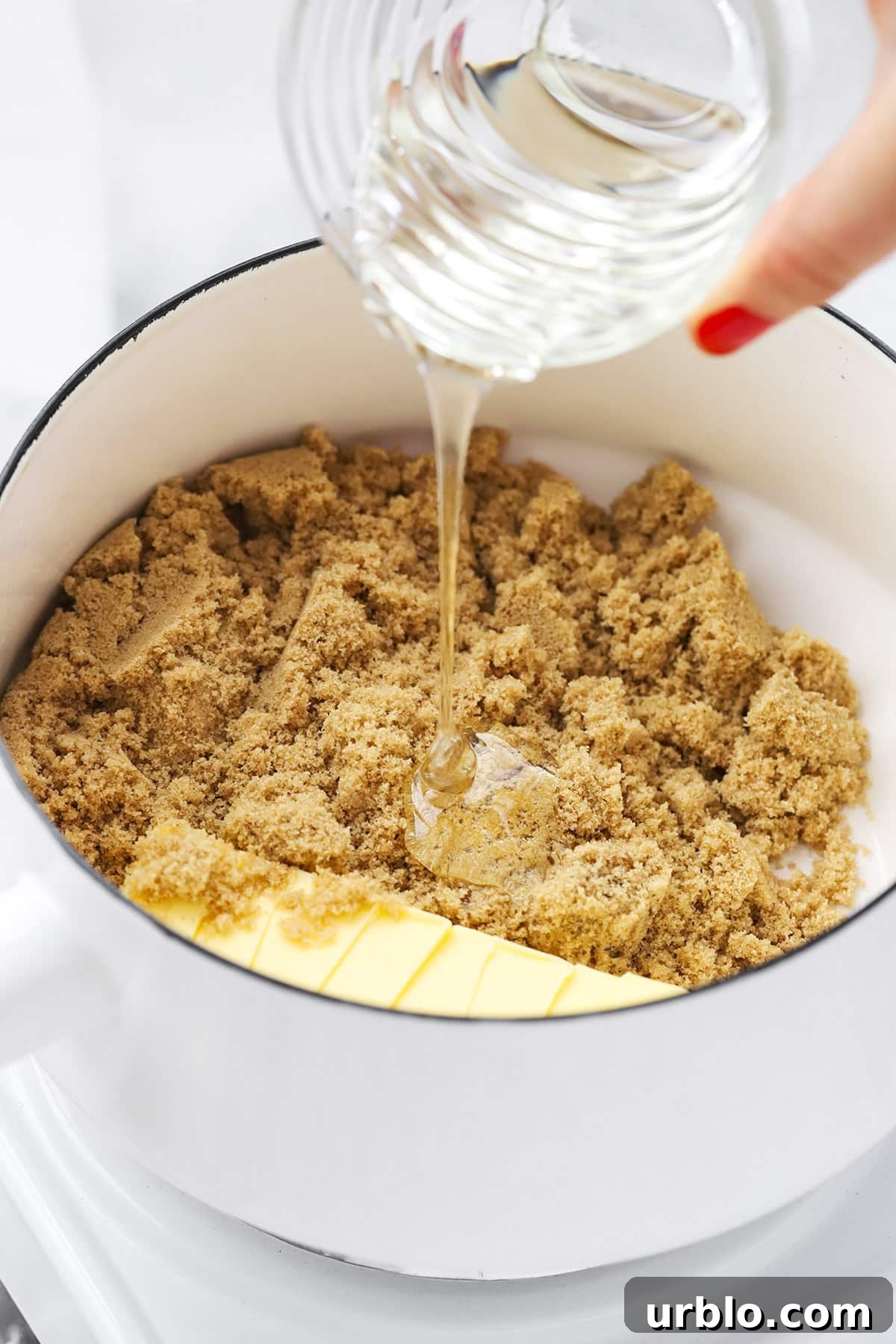 adding corn syrup to brown sugar and butter to make caramel sauce for homemade caramel corn