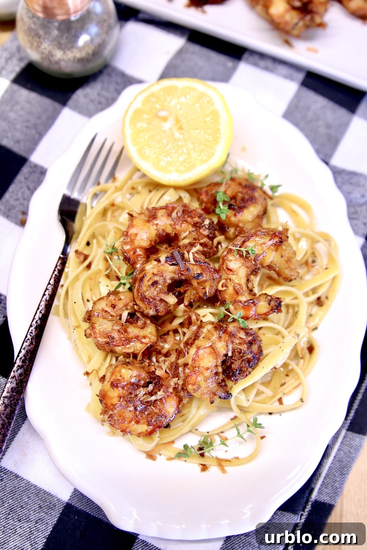 Grilled Shrimp over pasta on a platter with lemon half.