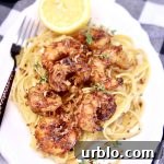 Platter of pasta and shrimp with half of a lemon.