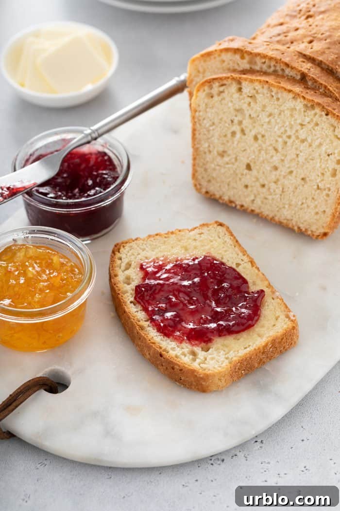 Slice of english muffin bread topped with jam set next to two small bowls of jam
