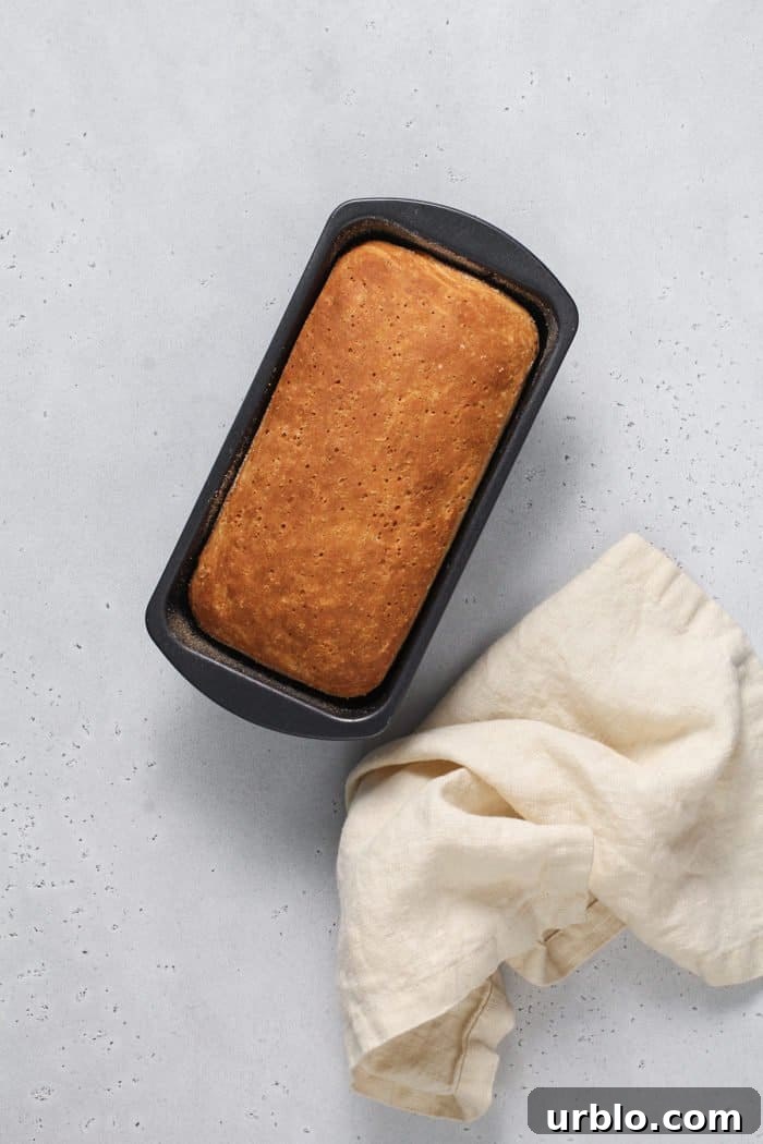 Baked loaf of english muffin bread cooling on a light colored countertop