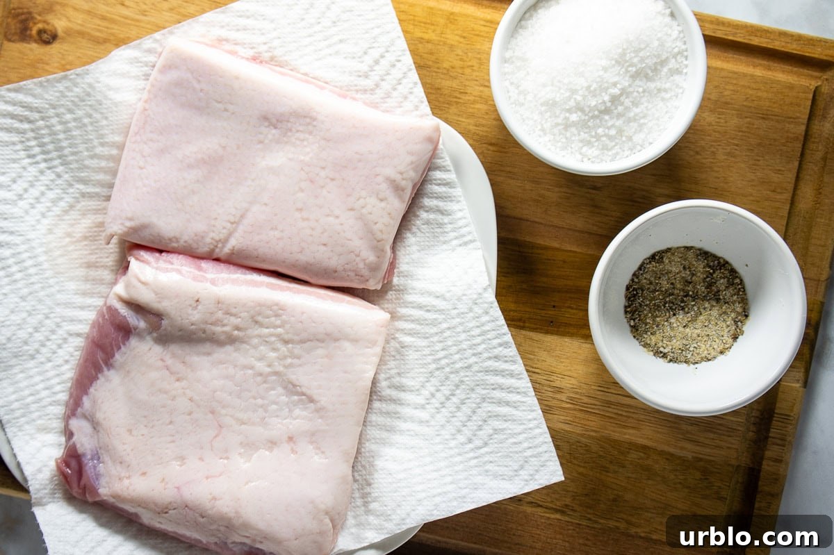 Crispy Salt-Crusted Pork Belly Recipe with Tender Juicy Meat 3 Ingredients to make a salt-crusted pork belly including bowls of salt and two slabs of pork belly.
