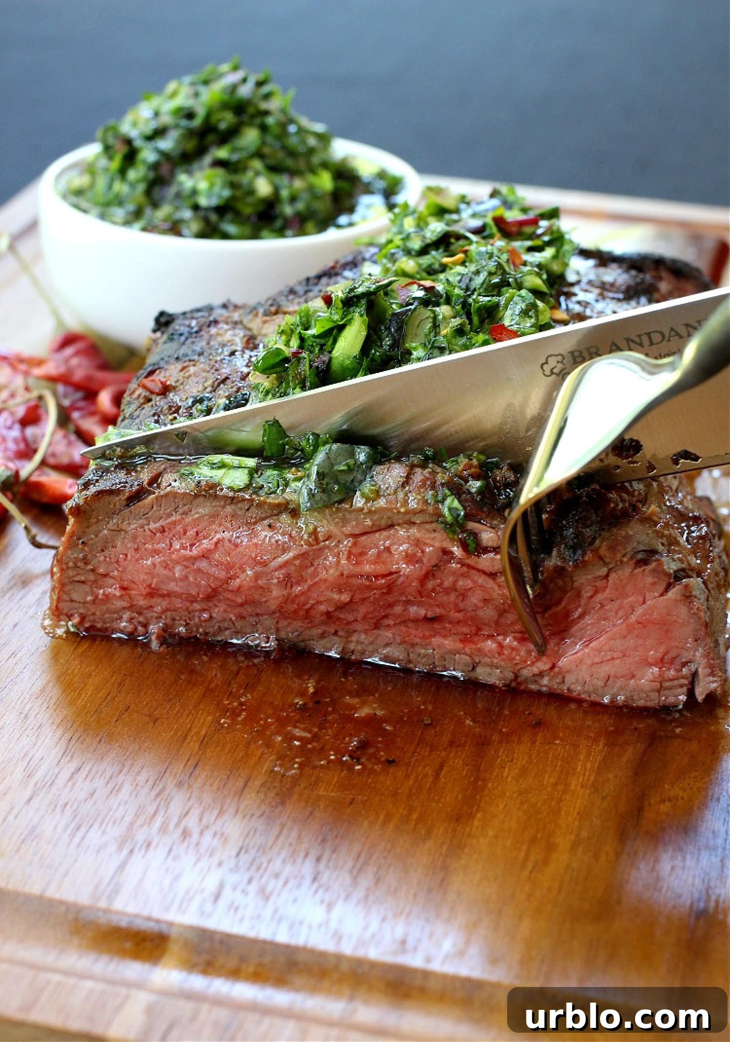 slicing steak with chimichurri sauce on top