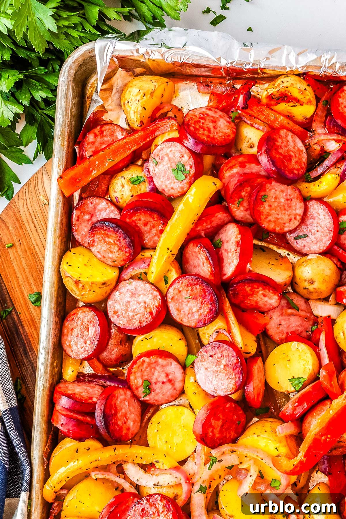 Sheet Pan Smoked Sausage with Roasted Potatoes 2 Smoked Sausage and Potatoes on a sheet pan and garnished with parsley.