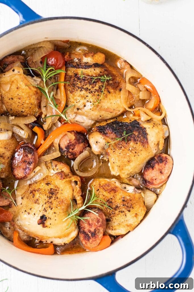 Scarpariello Chicken Recipe: Italian Peppers & Vinegar 2 A close up look at browned chicken thighs tucked into a bed of sauteed peppers, onions, and sausage.