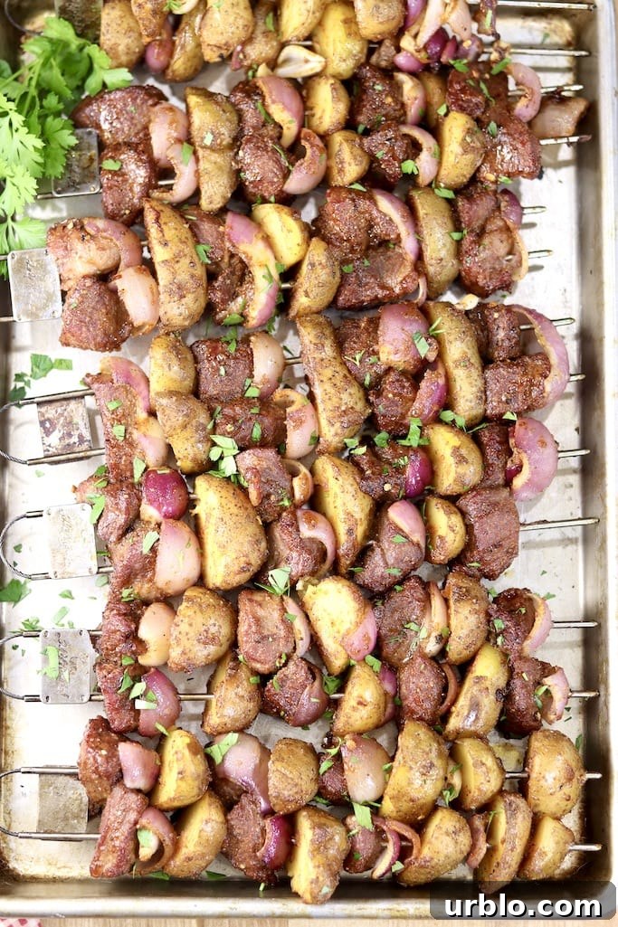 Steak and Potato Kabobs are a great dinner to make on the grill that the entire family will love. Just a few simple ingredients that you can prep ahead of time to make this quick and delicious meal. Steak and Potato Kabobs on a sheet pan, parsley garnish
