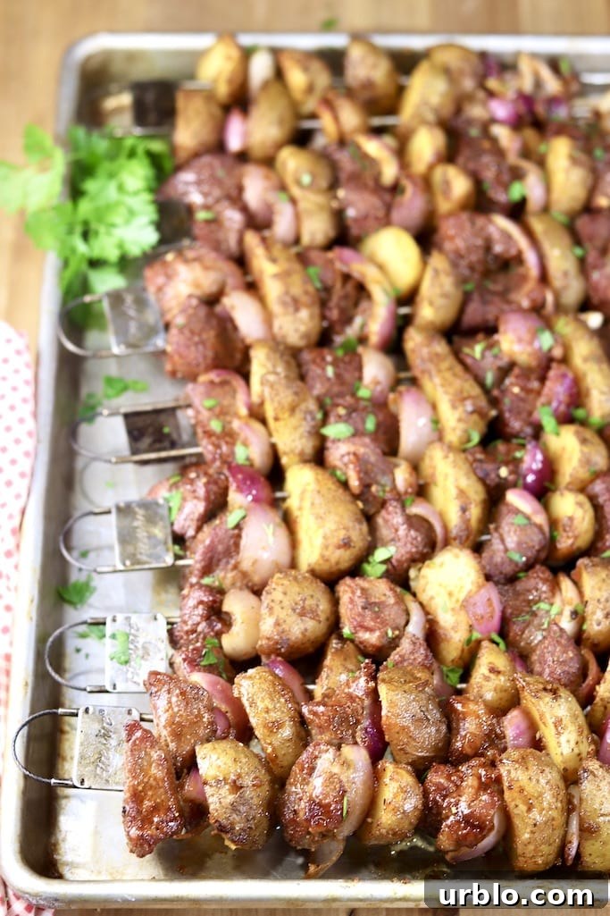 Steak Kabobs grilled with onions and potatoes. Seasoned with brown sugar garlic dry rub Sheet pan of grilled steak and potato kabobs, parsley garnish