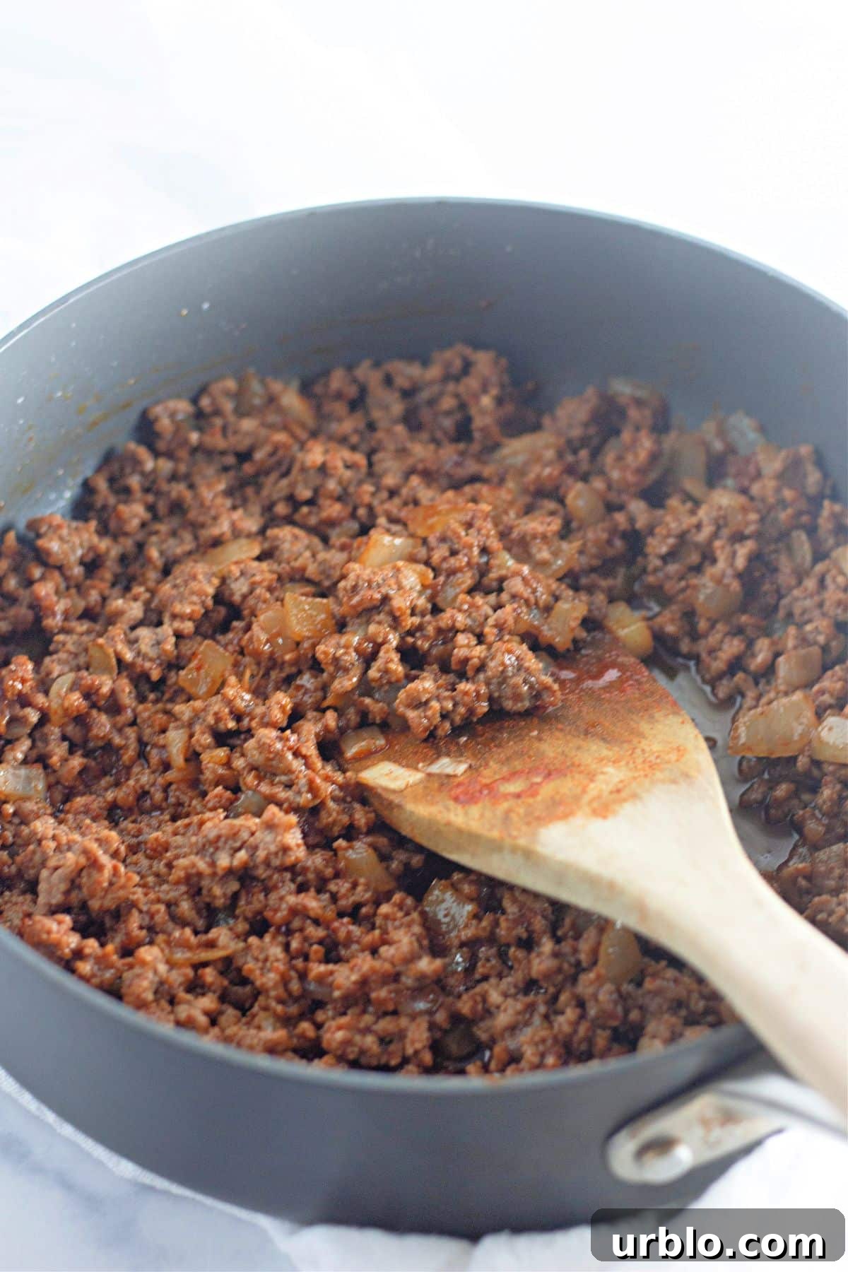 Cheesy Taco Ring with Crescent Roll Crust 5 taco seasoning being added to ground beef and onions in a large skillet.