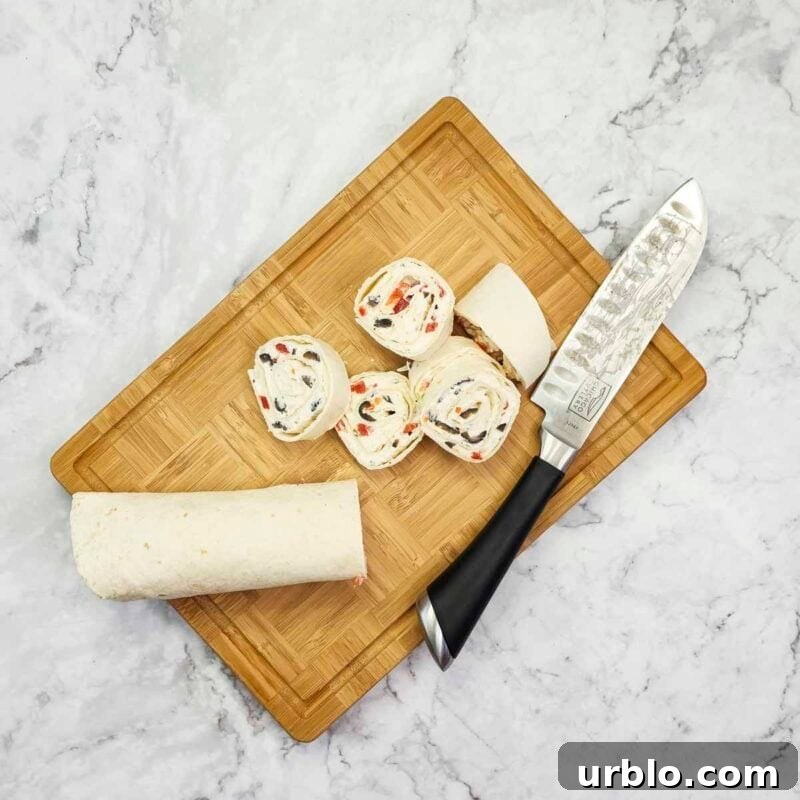 Creamy Ranch Pinwheels with Roasted Red Peppers Appetizer 9 Overhead view of process shot 6 - when ready to serve, remove the plastic and use a sharp knife to slice the rolled tortillas into rounds.